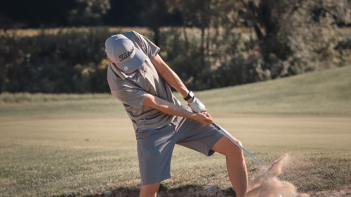 Golfer playing out of a bunker during a side competition