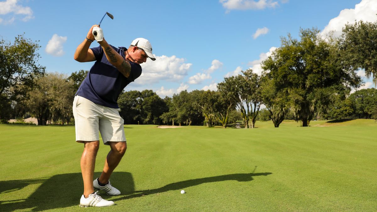 Golfer mid-swing on a sunny championship-style course